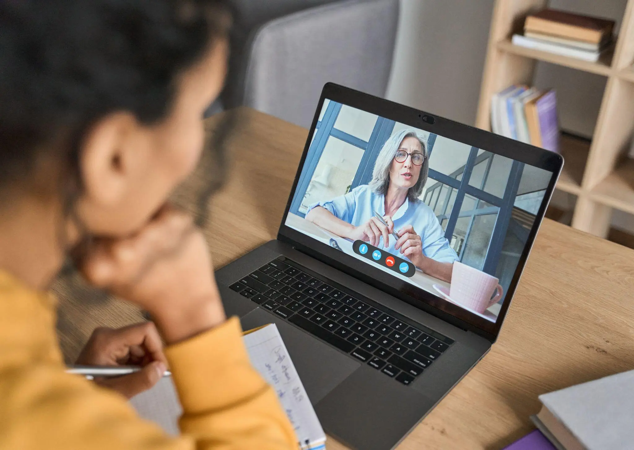 Online-Videokonferenz auf einem Laptop, eine Frau in hellblauer Bluse spricht
